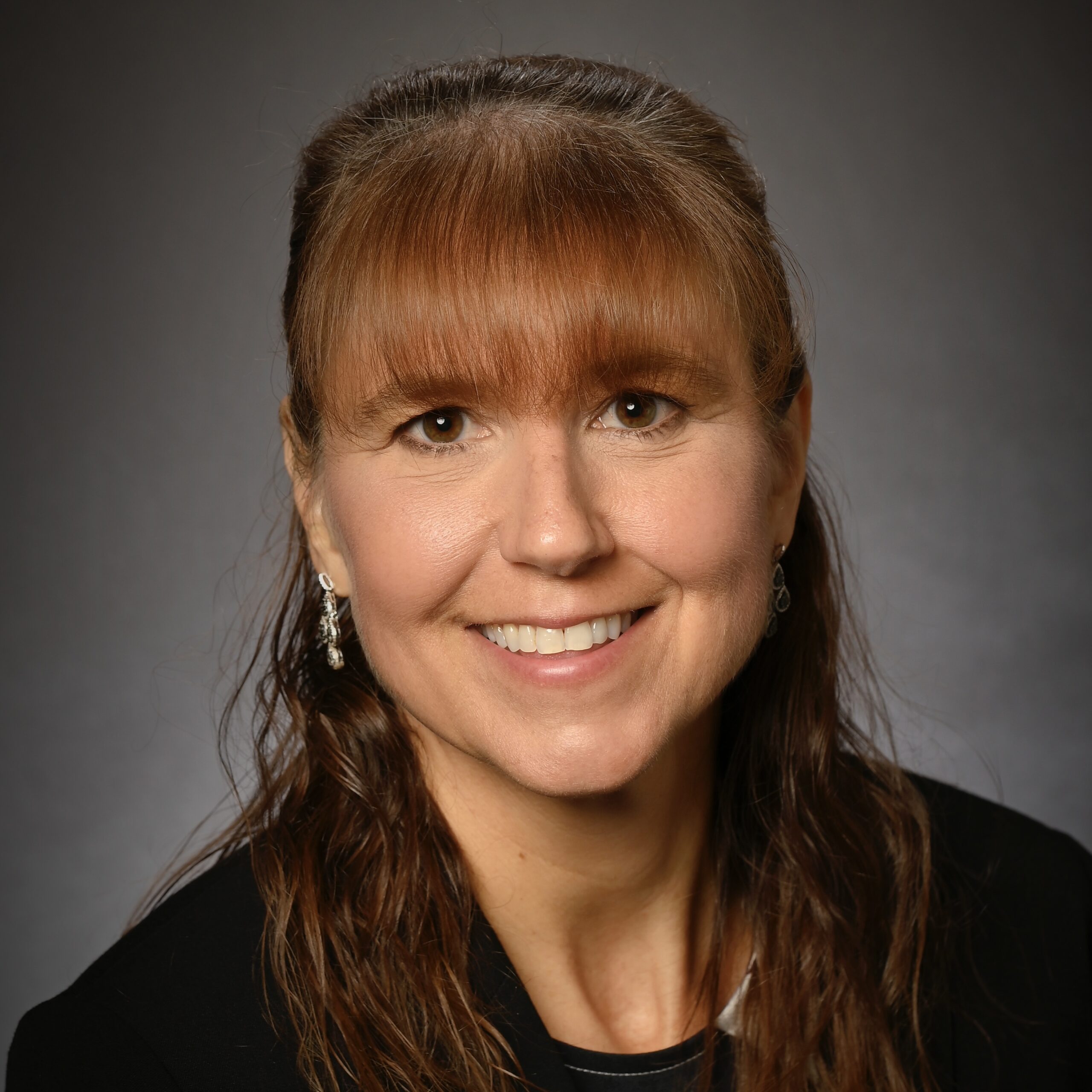 Smiling woman with brown hair and earrings